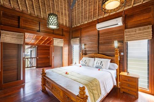 1 dormitorio con 1 cama grande en una habitación con paredes de madera en Gecko Villa & Bungalows en Lembongan
