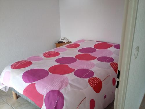 un lit dans une chambre avec un couvre-lit à pois dans l'établissement Appartement de vacances tout confort, à Narbonne-Plage