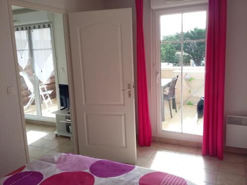 - une chambre avec un lit et une porte avec des rideaux roses dans l'établissement Appartement de vacances tout confort, à Narbonne-Plage