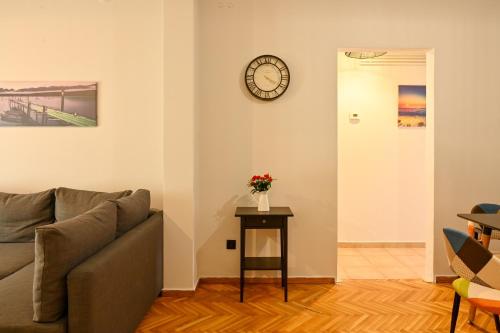 a living room with a couch and a clock on the wall at Thessaloniki Center Aristotelous Apartment in Thessaloniki