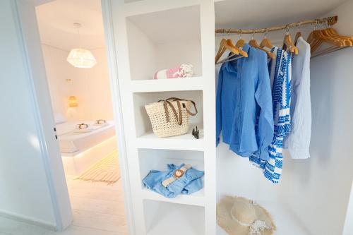 a closet with white shelves and blue clothes at The White Rose Hotel in Poros