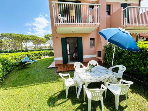 a table and chairs with an umbrella on a yard at Beachside Family Garden Retreat in Cavallino-Treporti