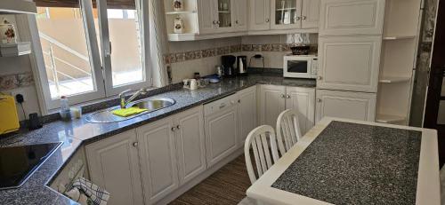 a kitchen with white cabinets and a sink and a table at Casa da Praia in Póvoa de Varzim