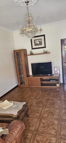 a living room with a television and a chandelier at Casa da Praia in Póvoa de Varzim