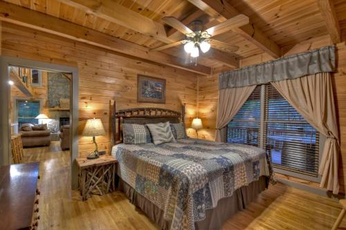 1 dormitorio en una cabaña de madera con cama y ventana en K6 Lodge Gather around the firepit soak in the hot tub and splash in the creek en Blue Ridge