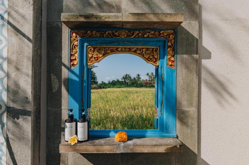 a window in a wall with a field in the background at Suga Estate - Rice Field View Villas in Ubud