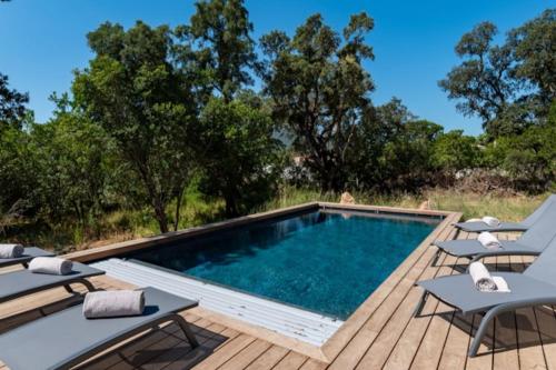 - une piscine sur une terrasse en bois avec des chaises dans l'établissement Villa Anaïak, à Zonza