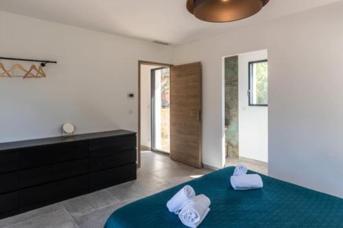 une chambre avec un lit bleu avec des serviettes dessus dans l'établissement Villa Anaïak, à Zonza