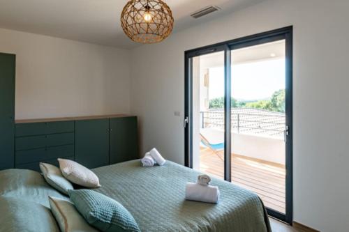 - une chambre avec un lit vert et un balcon dans l'établissement Villa Anaïak, à Zonza