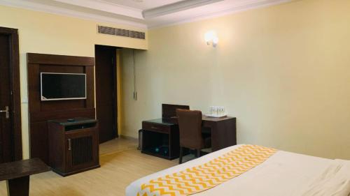 um quarto de hotel com uma cama, uma secretária e uma televisão em Hotel perial Inn - Nehru Palace em Nova Deli