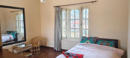 een slaapkamer met een bed, een spiegel en een raam bij Bodhi Homestay in Kathmandu