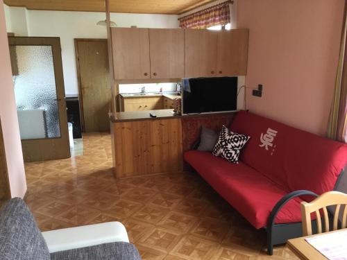 uma sala de estar com um sofá vermelho e uma cozinha em Amstetter’s Ferienwohnung em Waldenstein