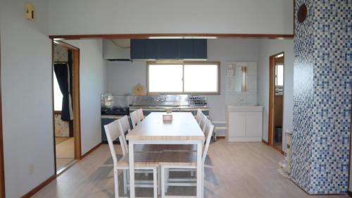 a dining room with a table and chairs in a kitchen at 東神楽大学ゲストハウス in Higashikagura