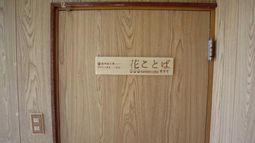 a sign on a wooden door with writing on it at 東神楽大学ゲストハウス in Higashikagura