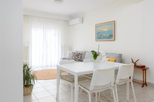 a white dining room with a white table and chairs at Mimoza's Sea View Apartment in Paleo Tsifliki
