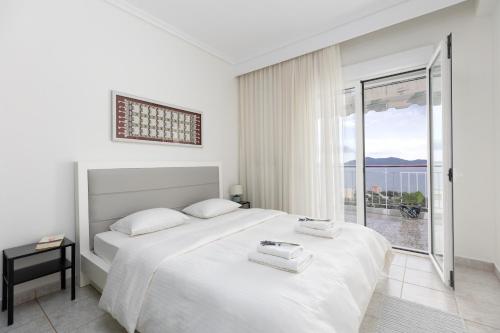 biała sypialnia z łóżkiem i dużym oknem w obiekcie Mimoza's Sea View Apartment w mieście Palaión Tsiflíkion