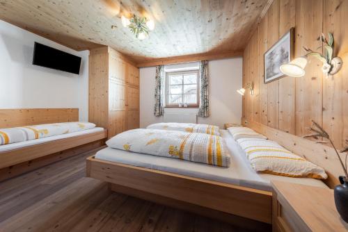 two beds in a room with wooden walls at Tlisöra Speckstube in Frena