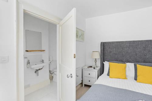 a bedroom with a bed with yellow pillows and a sink at 10 Clarence Hill - Elegant Town House with outside space in Dartmouth