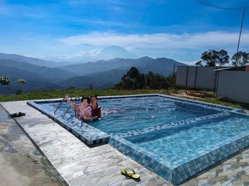 two children in a swimming pool with mountains in the background at Hawun Valley Kiulu in Tamparuli