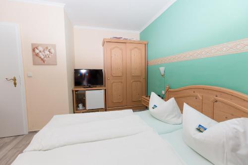 a bedroom with two white beds and a television at Haus Strandeck in Zingst