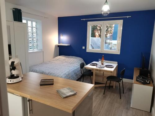 a bedroom with a bed and a desk with a table at Charmant studio à côté de la gare in Yvetot