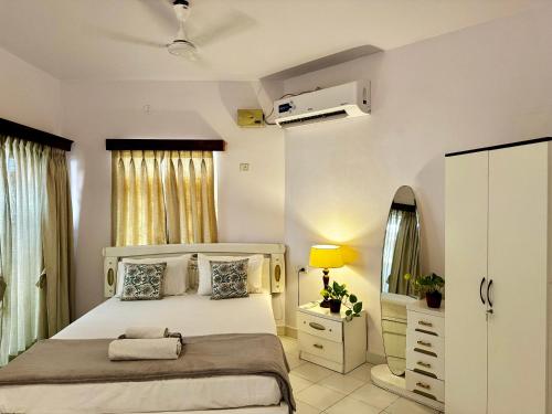 1 dormitorio con cama blanca y espejo en LUSO Beach Homes Goa en Benaulim