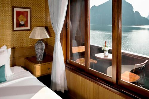 1 dormitorio con ventana, cama y mesa en Bhaya Halong Cruises, en Ha Long