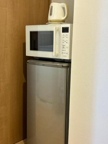 Un four micro-ondes est installé au-dessus d'un réfrigérateur. dans l'établissement CityStay難波南, à Osaka