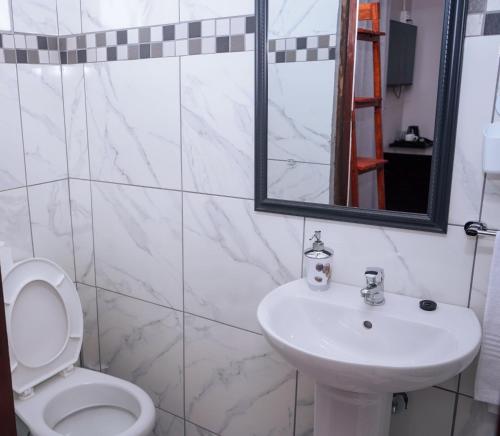 a bathroom with a sink and a toilet and a mirror at Safi Suites and Conference Centre in Mthatha