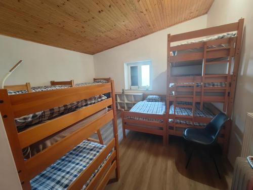 PodgorjeにあるTumova koča na Slavnikuの二段ベッド3台と椅子が備わる客室です。