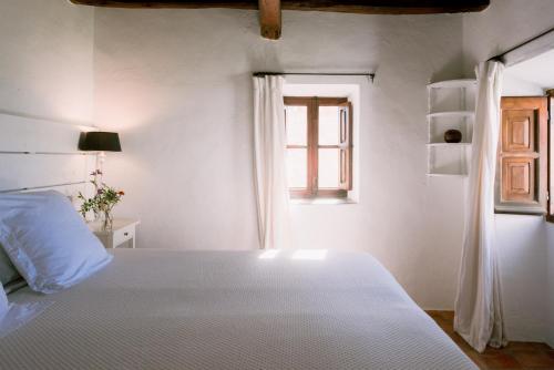 a white bedroom with a bed and a window at Can Quince Balafia Ibiza Hotel - Turismo de Interior in Sant Llorenç de Balafia