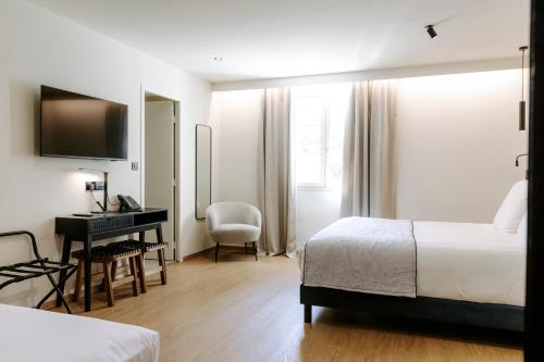 a hotel room with a bedroom with a desk and a bed at Soko Hotels-Pont du Gard in Remoulins