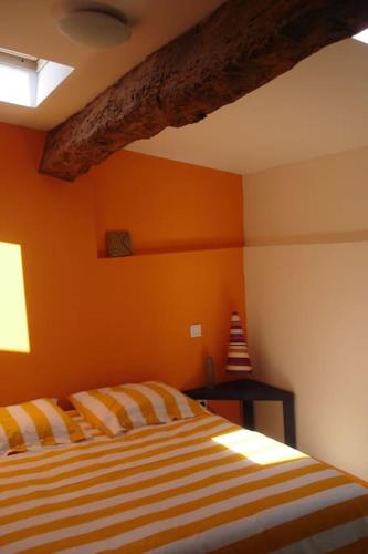 une chambre avec un lit avec un mur orange dans l'établissement Gite Chez Rosalie, à Grazac