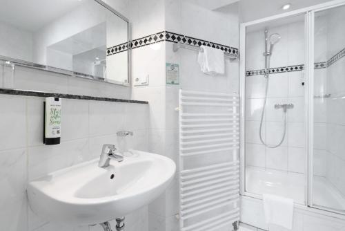 a white bathroom with a sink and a shower at Hotel Wegener in Mannheim