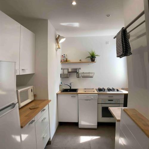une cuisine avec des placards blancs et des appareils électroménagers blancs dans l'établissement La Dune - 6p Arcachon center, terrasse 10m2, à Arcachon