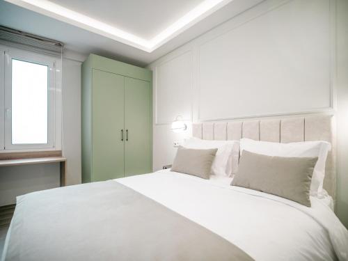 een slaapkamer met een groot wit bed met witte kussens bij ASTIKON Xenofontos Suites in Athene
