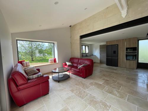 un salon avec deux chaises rouges et une table dans l'établissement Gîte Pierre de Jade, à Neuillé-Pont-Pierre