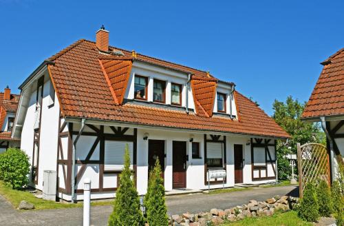 een wit huis met een oranje dak bij Ferienwohnung mit Balkon Gustow auf Rügen in Gustow