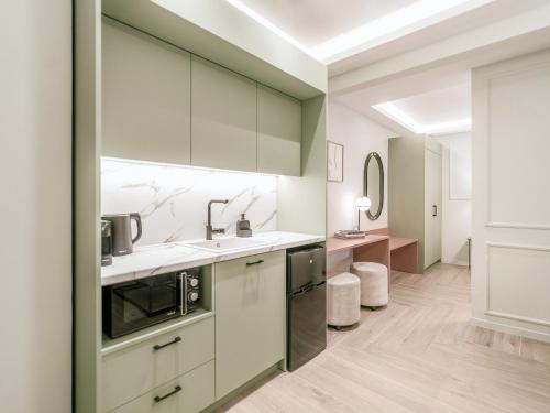 uma cozinha com armários brancos e um lavatório em ASTIKON Xenofontos Suites em Atenas