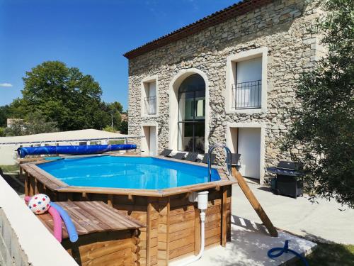 - une piscine en face d'une maison en pierre dans l'établissement Maison en pierres, à Fontanès