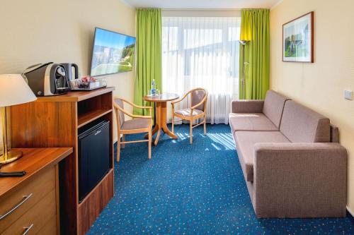 a hotel room with a couch and a table at AHORN Hotel Am Fichtelberg in Kurort Oberwiesenthal