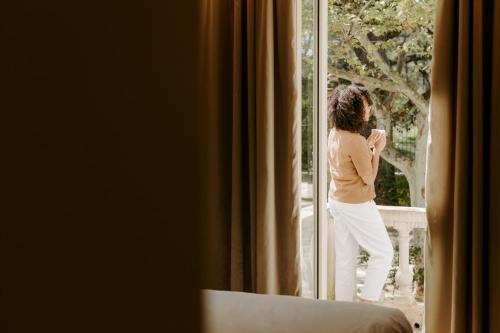 a woman is looking out of a window at Soko Hotels-Pont du Gard in Remoulins