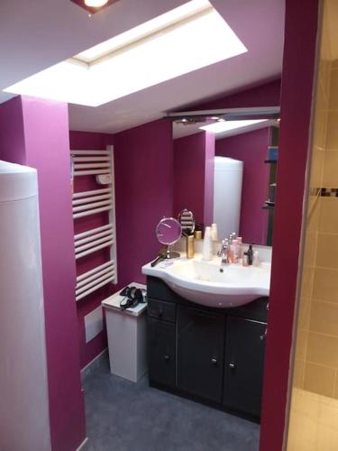 La salle de bains est pourvue d'un lavabo et d'un mur violet. dans l'établissement Chez Margaux, à Grazac