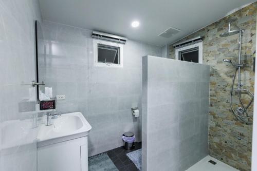a white bathroom with a shower and a sink at บ้านกันเอง Baan Kun Aeng Homestay in Ban Kat Nua