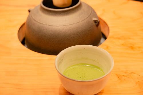 una taza de líquido verde sobre una mesa de madera en Matsumoto Tourist Hotel en Matsumoto
