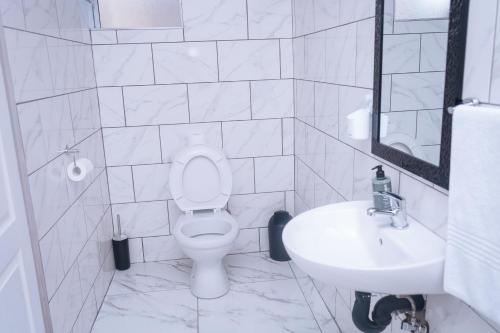 a white bathroom with a toilet and a sink at Safi Suites and Conference Centre in Mthatha
