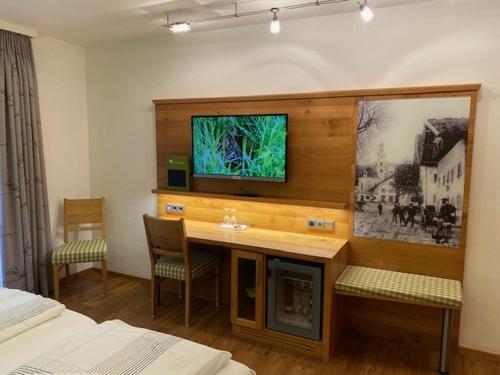 a room with a desk and a tv on the wall at Hotel am Wiesenhang - Garni in Bad Kohlgrub