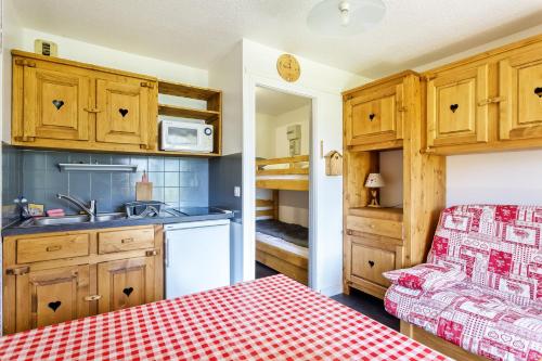 une cuisine avec des armoires en bois et une table à carreaux rouges dans l'établissement L'étoile des Neiges - Studio sur les pistes Manigod, à Manigod