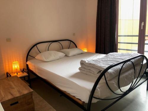 een bed met witte lakens en kussens in een slaapkamer bij Duinroos C2 in Koksijde