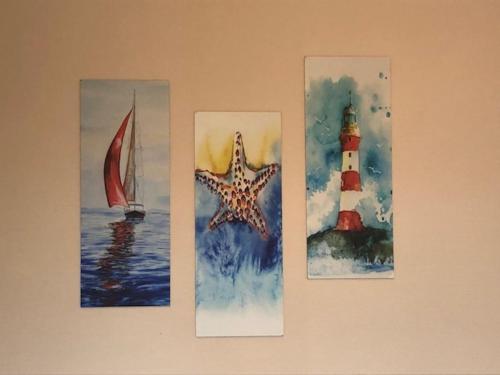 three pictures of a lighthouse and a starfish on a wall at Duinroos C2 in Koksijde